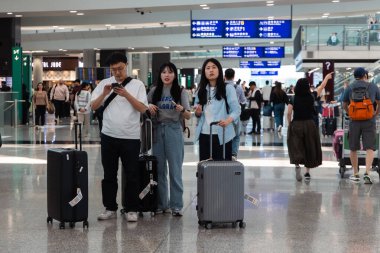 Hong Kong, Çin - 21 Mart 2024: Hong Kong Uluslararası Havaalanı 'ndaki varış salonunda bavullu turist grubu