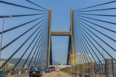Hong Kong, Çin - 21 Mart 2024 - Arabalar güneşli bir günde Hong Kong 'da kablo destekli modern bir köprüden geçiyor