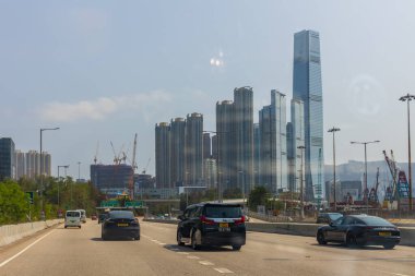 Hong Kong, Çin - 21 Mart 2024 Arkasında şehir manzarası ve yüksek gökdelenleri olan bir otoyolda arabalar sürüyor