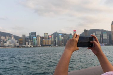 Lady Hand bir akıllı telefon kamerası tutuyor. Çin, Hong Kong 'un güzel ufuk çizgisini yakalıyor.