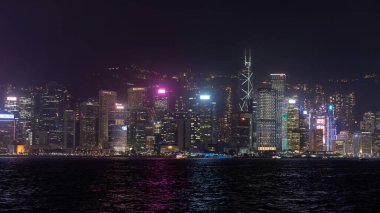 Hong Kong, Çin - 22 Mart 2024: Hong Kong gökdelenleri geceleri modern ofis binalarının suya yansımasıyla aydınlanıyor