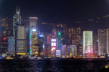 Hong Kong, Çin - 22 Mart 2024: Hong Kong gökdelenleri geceleri modern ofis binalarının suya yansımasıyla aydınlanıyor