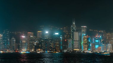 Hong Kong, Çin - 22 Mart 2024: Hong Kong gökdelenleri Victoria Limanı 'ndan geçen binaların ve teknelerin ışık huzmeleriyle gece parlıyor