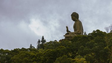 Mars bronz Buda heykeli bulutların üstündeki bir dağın tepesinde huzur içinde duruyor ve etrafı yeşil ormanlarla çevrili.