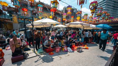 Hong Kong, Çin - 24 Mart 2024: Koruma maskesi takan turistler ve yerliler Hong Kong 'daki Wong Tai sin Tapınağı' nda tütsü çubuklarıyla dua ediyorlar.