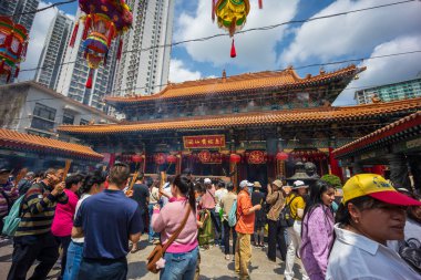 Hong Kong, Çin - 24 Mart 2024: Koruma maskesi takan turistler ve yerliler Hong Kong 'daki Wong Tai sin Tapınağı' nda tütsü çubuklarıyla dua ediyorlar.
