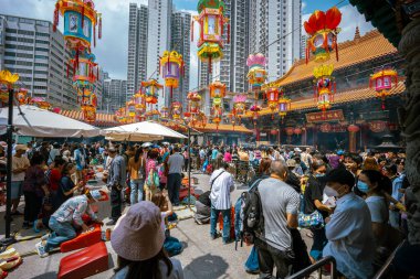 Hong Kong, Çin - 24 Mart 2024: Çin Yeni Yılı için renkli fenerlerle süslenmiş Wong Tai Sin Tapınağı 'nın dışında toplanan turistler ve yerel halk