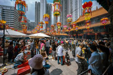 Hong Kong, Çin - 24 Mart 2024: Çin Yeni Yılı için renkli fenerlerle süslenmiş Wong Tai Sin Tapınağı 'nın dışında toplanan turistler ve yerel halk