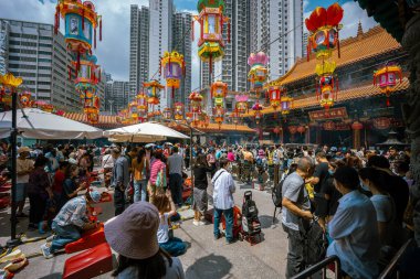 Hong Kong, Çin - 24 Mart 2024: Çin Yeni Yılı için renkli fenerlerle süslenmiş Wong Tai Sin Tapınağı 'nın dışında toplanan turistler ve yerel halk