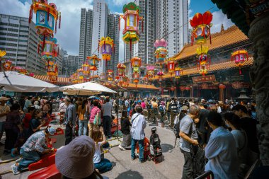 Hong Kong, Çin - 24 Mart 2024: Çin Yeni Yılı için renkli fenerlerle süslenmiş Wong Tai Sin Tapınağı 'nın dışında toplanan turistler ve yerel halk