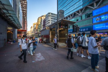 Hong Kong, Çin - 24 Mart 2024: Hong Kong 'un alışveriş bölgesindeki yoğun bir caddeden geçen turistler ve vatandaşlar, başlarının üzerinde reklam panoları olan