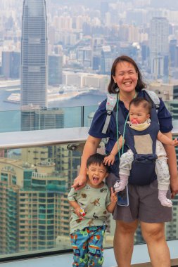 Hong Kong 'da güneşli bir günün tadını çıkaran Asyalı bir aile fotoğraf için poz veriyor.