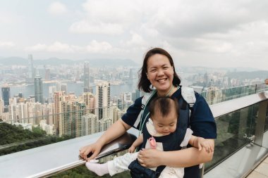 Anne bebeğini kucağında Hong Kong, Çin 'in ufuk çizgisine bakarken tutuyor.