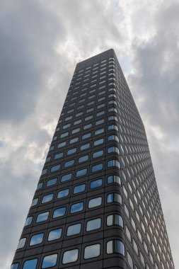 Modern ofis binası pencereleri tekrar eden bulutlu bir gökyüzüne karşı dimdik ayakta duruyor Hong Kong, Çin