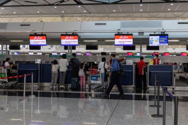 Hong Kong, Çin - 26 Mart 2024: kalabalık havaalanı terminali gişede kayıt için sırada bekleyenler var. Bavulu olan yolcular modern bir şekilde uluslararası uçuşlara hazırlanıyorlar..