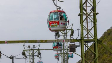 Hong Kong, Çin - 22 Mart 2024: Ocean Park Hong Kong 'da güzel bir okyanus kıyısına bakan manzaralı bir manzaraya giden teleferiğe binen turistler.