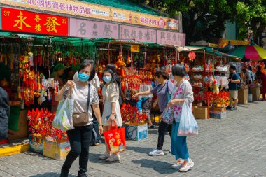 Hong Kong, Çin - 24 Mart 2024: Yüz maskesi takan insanlar Çin 'deki yeni yıl dekorasyonları için açık hava pazarında alışveriş yapıyorlar