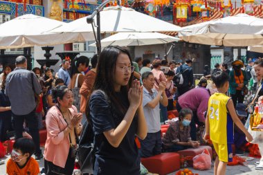 Hong Kong, Çin - 24 Mart 2024: Genç bir kadın gözlerini kapatıp dua ederken ellerini birarada tutuyor