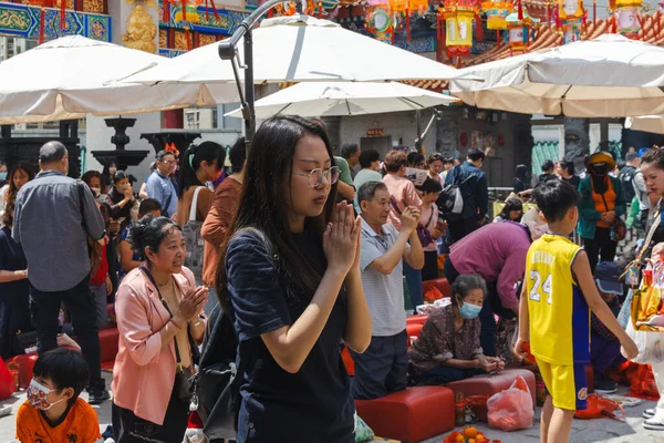 Hong Kong, Çin - 24 Mart 2024: Genç bir kadın gözlerini kapatıp dua ederken ellerini birarada tutuyor