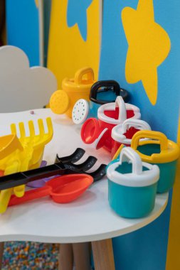 Renkli plastik oyuncaklar oyun odasındaki beyaz bir masanın üzerinde, çocukların oynaması için hazırlar.