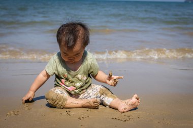 Asyalı çocuk kumsalda kumsalda oynuyor.