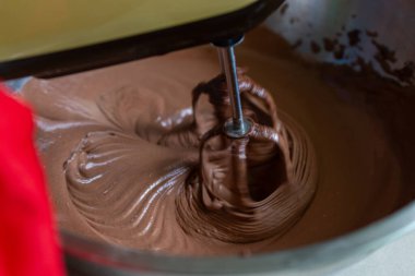 Elektrikli mikser, lezzetli bir tatlı yapmak için çikolatalı kremayı kaseye karıştırmaktır.