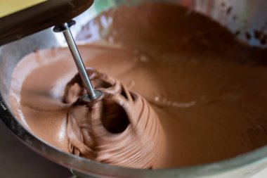Elektrikli mikser, lezzetli bir tatlı yapmak için çikolatalı kremayı kaseye karıştırmaktır.