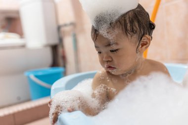 Sabun köpüğüyle kaplanmış küçük bir küvette banyo yapıyor.