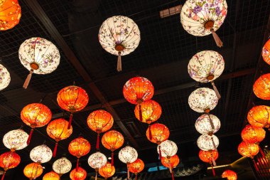 Tavandan sarkan çiçek desenli kırmızı ve beyaz fenerler Çin 'in yeni yılını kutluyor.
