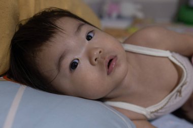 Meraklı bir çocuk, düşünceli bir ifadeyle doğrudan kameraya bakıyor..