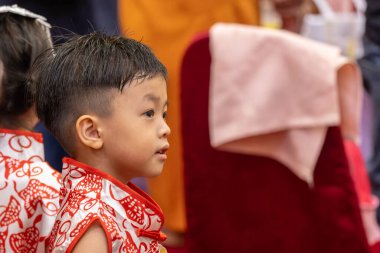 Genç bir çocuk, neşeyle parıldıyor, geleneksel Çin kıyafetleri giyiyor..