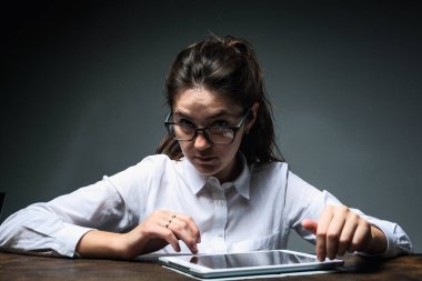 Gözlüklü kız evde bilgisayarla çalışıyor ve çevrimiçi yayın yapıyor. Tahta masadaki kız. Yaratıcı kız.  