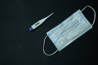 Arka planda koruyucu maske ve termometre var. Koronavirüse karşı koruma. Sosyal uzaklık