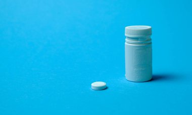 Elin bir hap tutuyor. Virüsün tedavisini ara. Mavi bir arkaplanda.