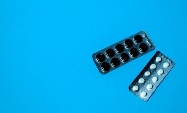 Elin bir hap tutuyor. Virüsün tedavisini ara. Mavi bir arkaplanda.