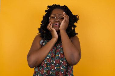 Üzgün, ağlayan, sarı arka plan üzerine gözlük takan genç, Afro-Amerikan bir kadın karısı ya da kız arkadaşı ile tartıştıktan sonra depresyona giriyor, stresli görünüyor, suratını asıyor, yakışıklı bir erkek kendini yalnız ve endişeli hissediyor.