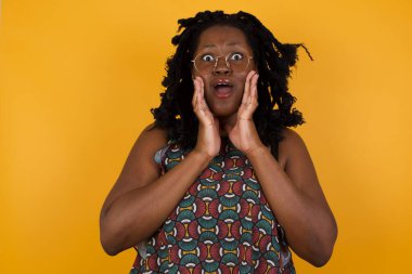 Ürkmüş genç, Afro-Amerikan gözlüklü, sarı arka planda güzel bir kadının atölyedeki fiyatlarla şok olmuş, bir şey alacak parası kalmamış, insan ve insan duyguları kavramı.