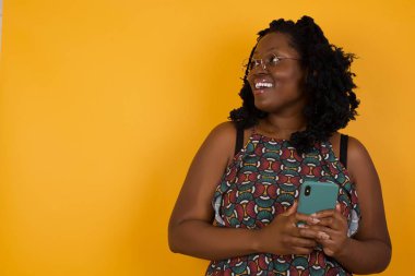 Çekici modelin, sarı arka plandaki kız arkadaşı sersemletirken sosyal medyada oluşan gözlük takan güzel Afro-Amerikan kadının fotosu. 