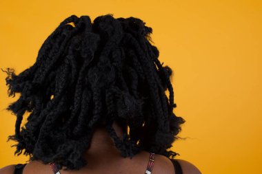 Sarı arka planda gözlük takan güzel bir Afro-Amerikan kadının arka plan çekimi..