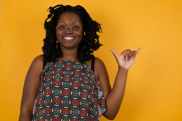 Young beautiful afro american woman wearing glasses over yellow background showing up number six Liu with fingers gesture in sign Chinese language