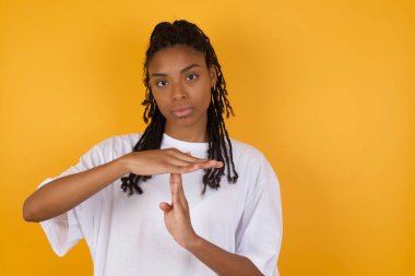 Afro-Amerikalı kadın sarı arka planda sevişme hareketi yapıyor. 