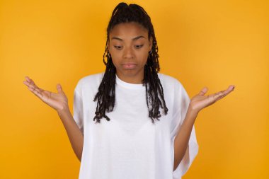 Afrikalı Amerikalı kadının sarı arka planda çaresiz bir jest yaptığından emin değilim. 