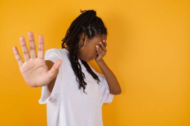 Korkan Afrikalı Amerikalı kadın sarı arka plan ve örtülü gözlere karşı 