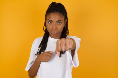 Öfkeli Afrikalı Amerikalı kadın sarı arka planda savaşıyor., 