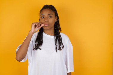 Afrikalı Amerikalı kadın sarı arka planda dudaklarını kapatıyor. 