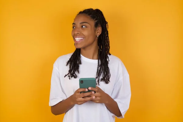 Riéndose Mujer Afroamericana Contra Fondo Amarillo Sosteniendo Teléfono Inteligente Móvil — Foto de Stock