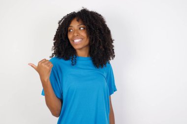 Çekici, kıvırcık saçlı, günlük mavi gömlekli, beyaz arka plan organizatörüne karşı duran, fotokopi odasına bakan, reklamları olan Afrikalı bir kadın. 