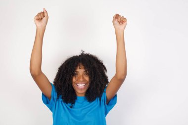 Bağrışmalar güzel, kıvırcık saçlı, günlük mavi gömlekli, beyaz arka planda duran Afrikalı bir kadın. 