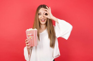 Patlamış mısırlı güzel bir kadın dürbün gibi jest yapıyor. Dürbün gibi dilini çıkarıyor, gözler parmaklarından bakıyor. Çılgın ifade.