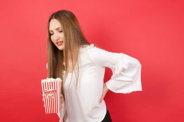 Patlamış mısırlı güzel bir kadın sırt ağrısı çekiyor, elleriyle dokunuyor, kas ağrısı çekiyor.